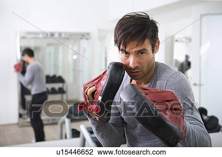 Stock Image - Trainer wearing padded gloves in gym. Fotosearch
