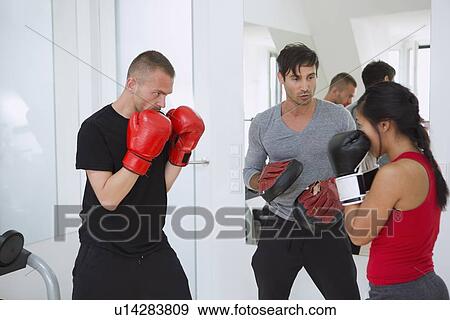 Stock Photo - Trainer working with boxers in gym. Fotosearch