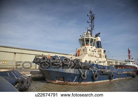 Tug boat docked in urban harbor View Large Photo Image Stock Image - Tug boat docked in urban harbor. Fotosearch