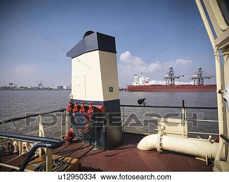 Picture - Tugboat docked in urban harbor. Fotosearch