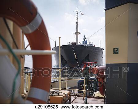 Stock Photography - Tugboat pulling ship in ocean. Fotosearch