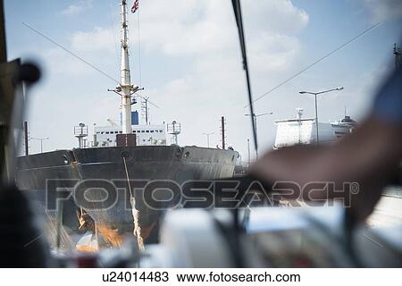 Tugboat pulling ship in urban harbor View Large Photo Image Stock Image - Tugboat pulling ship in urban harbor. Fotosearch