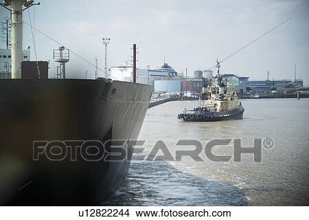 Tugboat sailing in urban harbor View Large Photo Image Picture - Tugboat sailing in urban harbor. Fotosearch