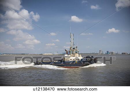 Tugboat sailing in urban harbor View Large Photo Image Stock Image - Tugboat sailing in urban harbor. Fotosearch