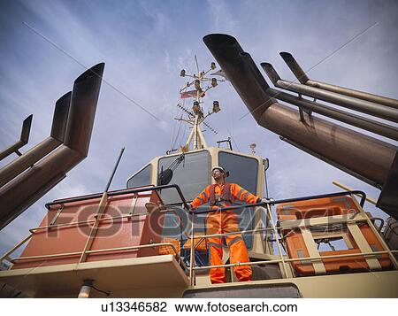 Tugboat worker standing on deck View Large Photo Image Stock Image - Tugboat worker standing on deck. Fotosearch