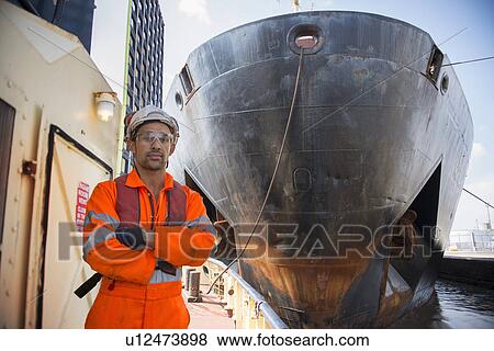 Stock Photo - Tugboat worker standing on deck. Fotosearch