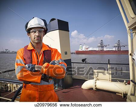 Tugboat worker standing on deck View Large Photo Image Stock Photograph - Tugboat worker standing on deck. Fotosearch