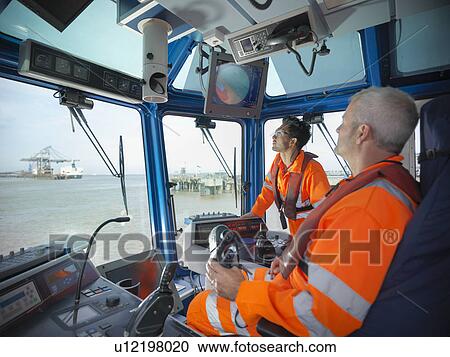 Stock Image - Tugboat workers in wheelhouse. Fotosearch