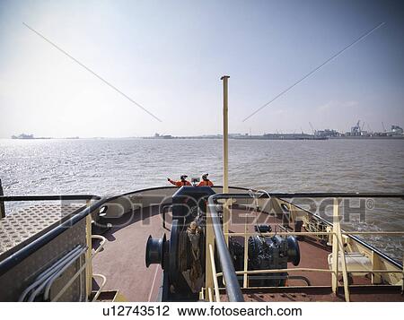 Tugboat workers standing on deck View Large Photo Image Stock Image - Tugboat workers standing on deck. Fotosearch