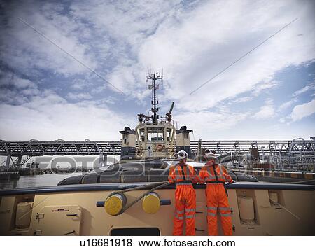 Stock Photo - Tugboat workers standing on deck. Fotosearch