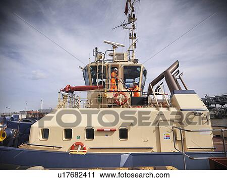 Stock Image - Tugboat workers walking on bridge. Fotosearch