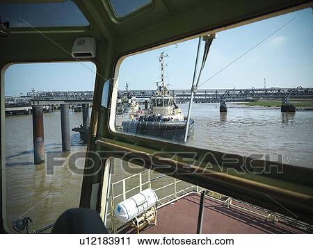 Stock Image - Tugboats in urban harbor. Fotosearch