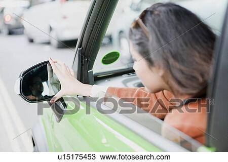 Stock Image - Woman adjusting side mirrors. Fotosearch