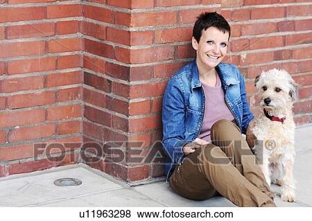 Woman and dog sitting on city street View Large Photo Image Stock Photo - Woman and dog sitting on city street. Fotosearch