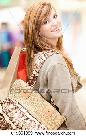 Stock Photo - Woman carrying shopping bags in mall. Fotosearch