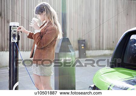 Woman charging electric car on street View Large Photo Image Stock Photo - Woman charging electric car on street. Fotosearch