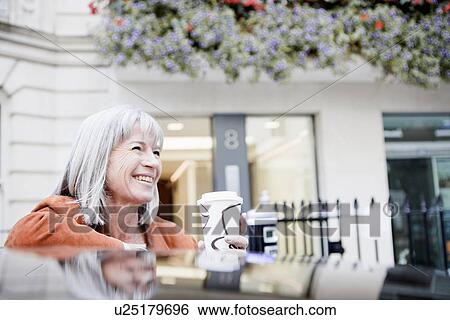 Stock Photograph - Woman drinking coffee on city street. Fotosearch