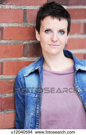 Woman leaning against brick wall View Large Photo Image Picture - Woman leaning against brick wall. Fotosearch