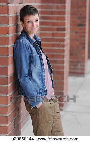Picture - Woman leaning against brick wall. Fotosearch