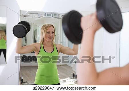 Woman lifting weights in gym View Large Photo Image Stock Photo - Woman lifting weights in gym. Fotosearch