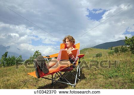Woman reading in lawn chair on hillside View Large Photo Image Stock Image - Woman reading in lawn chair on hillside. Fotosearch