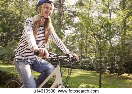 Stock Photo - Woman riding bicycle on rural road. Fotosearch