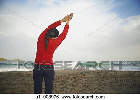 Stock Photograph - Woman stretching on beach. Fotosearch