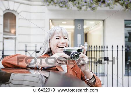 Stock Photo - Woman taking picture on city street. Fotosearch