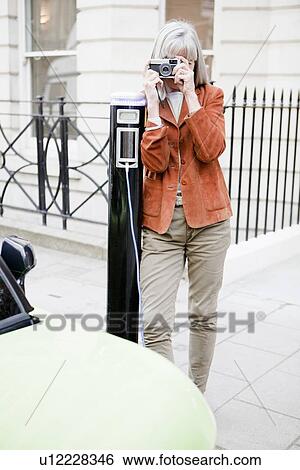Woman taking picture on city street View Large Photo Image Stock Photograph - Woman taking picture on city street. Fotosearch