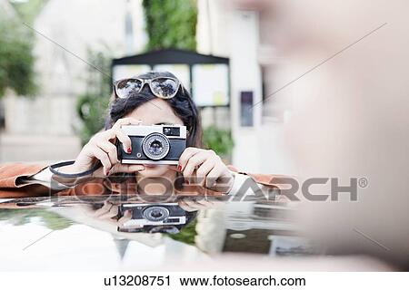 Stock Image - Woman taking pictures on city street. Fotosearch