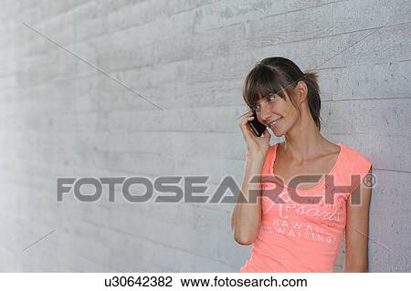 Stock Image - Woman talking on cell phone outdoors. Fotosearch