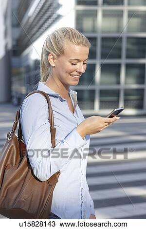 Woman using cell phone on city street View Large Photo Image Stock Image - Woman using cell phone on city street. Fotosearch