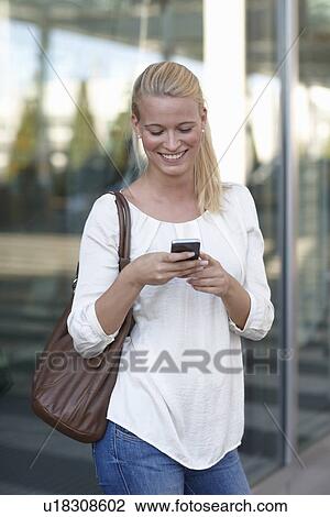 Woman using cell phone on city street View Large Photo Image Stock Image - Woman using cell phone on city street. Fotosearch