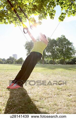 Stock Photo - Woman using exercise straps outdoors. Fotosearch