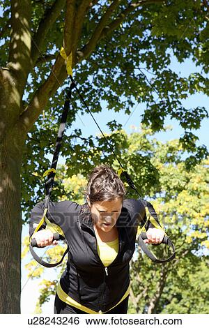 Stock Photograph - Woman using exercise straps outdoors. Fotosearch