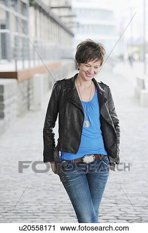 Stock Image - Woman walking on city street. Fotosearch