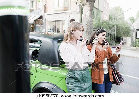 Women applying lipstick on city street View Large Photo Image Stock Image - Women applying lipstick on city street. Fotosearch