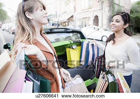 Stock Image - Women loading shopping bags in car. Fotosearch
