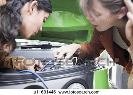 Stock Photograph - Women plugging in electric car. Fotosearch
