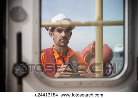 Worker on tug boat holding binoculars View Large Photo Image Picture - Worker on tug boat holding binoculars. Fotosearch