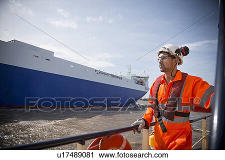 Stock Image - Worker on tug boat overlooking ocean. Fotosearch