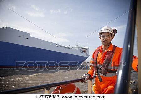 Stock Image - Worker on tug boat overlooking ocean. Fotosearch