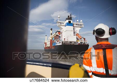 Worker on tug boat overlooking ship View Large Photo Image Picture - Worker on tug boat overlooking ship. Fotosearch