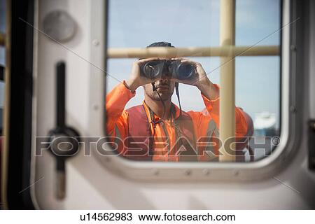 Worker on tug boat using binoculars View Large Photo Image Stock Image - Worker on tug boat using binoculars. Fotosearch