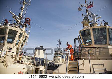Worker standing on deck of tow boat View Large Photo Image Stock Image - Worker standing on deck of tow boat. Fotosearch