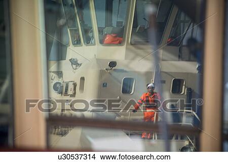 Worker standing on deck of tug boat View Large Photo Image Picture - Worker standing on deck of tug boat. Fotosearch