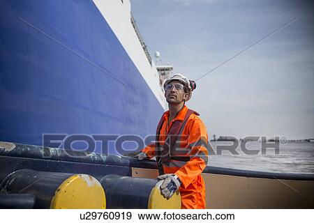 Stock Photo - Worker standing on tug boat. Fotosearch