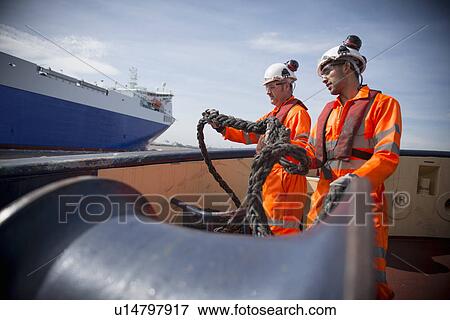 Stock Photo - Workers on tug boat holding rope. Fotosearch
