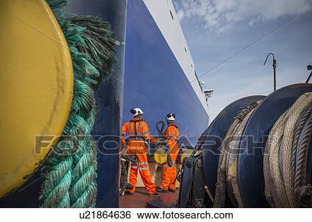 Stock Photograph - Workers on tug boat holding rope. Fotosearch