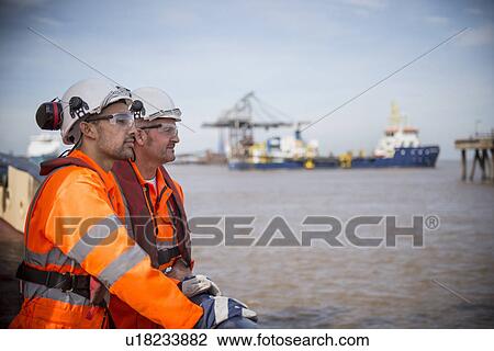 Stock Image - Workers on tug boat overlooking ocean. Fotosearch